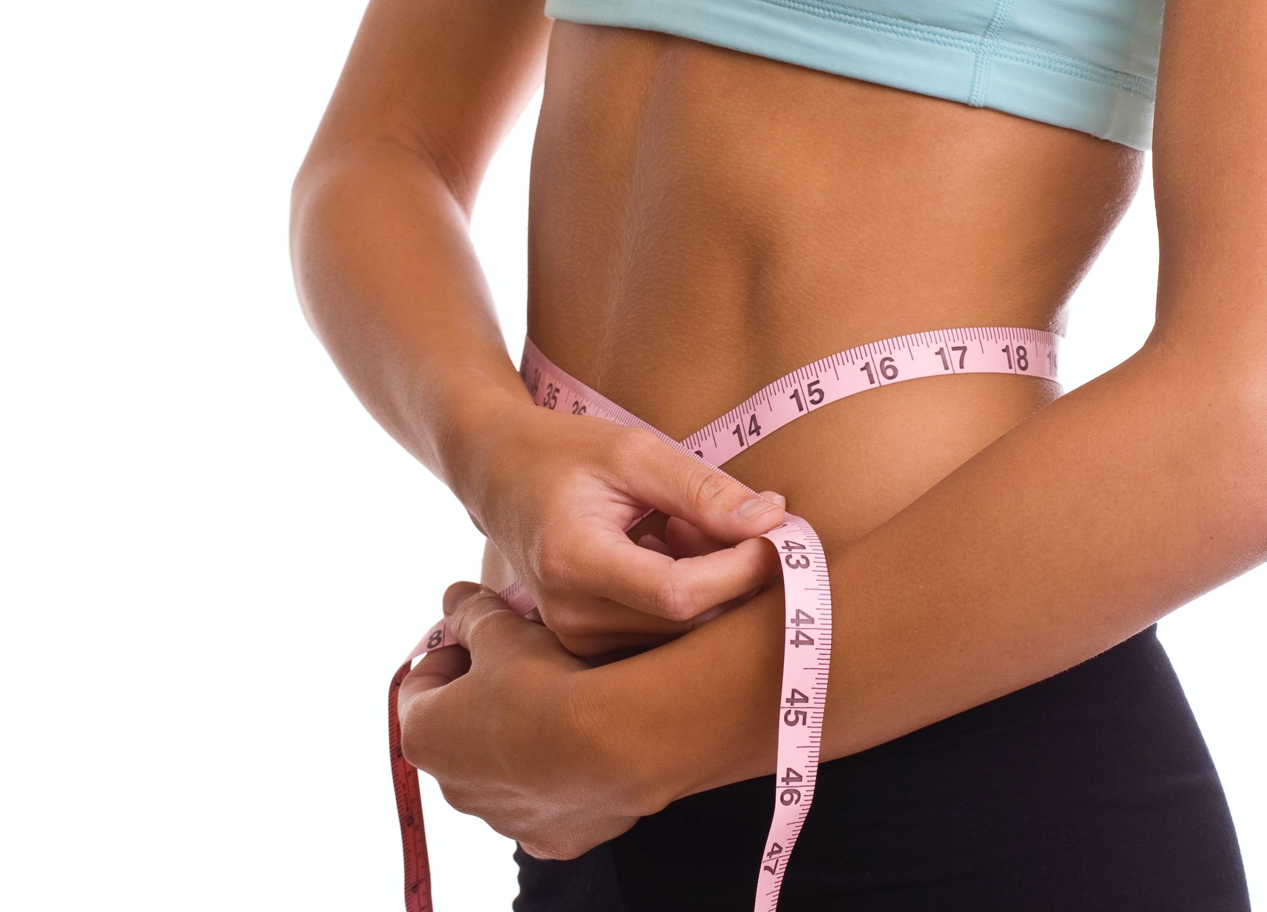 Fit woman measuring her waistline. 